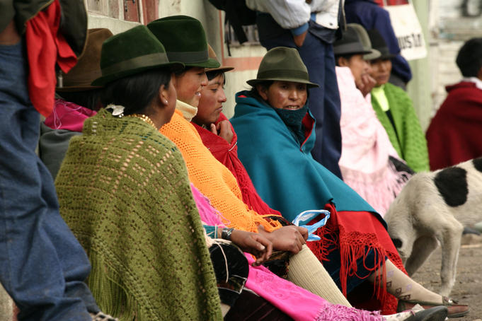 Women sitting in colourful ponchos and hats.