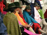Women sitting in colourful ponchos and hats.
