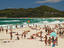 People on the beach with lighthouse in the distance.