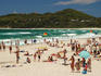 People on the beach with lighthouse in the distance.