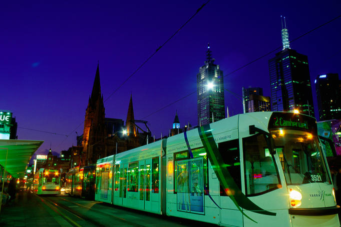 Tram stops for passengers in city at night.