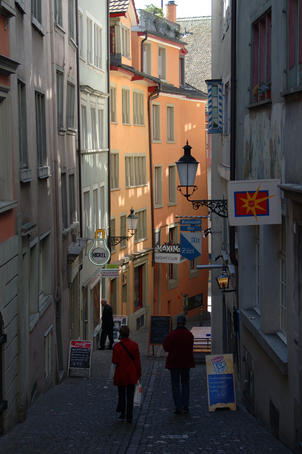 People walking down a small cobble-stoned alley lined with restaurants, bars and shops, Niederdorf (old town).