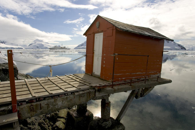 An abandoned Argentine base shed overhanging on a pier, Almirante Brown.