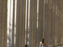 Woman walking past large concrete columns supporting a government building.