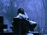 Snow-dusted statue on headstone at Powazki Cemetery.
