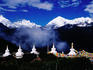 Buddhist stupas and prayer flags with Meili Xueshan mountain range in background.