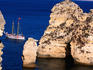 Coastline, rock formations, yacht in distance.