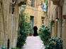 A priest walks a narrow laneway in historic Vittoriosa.