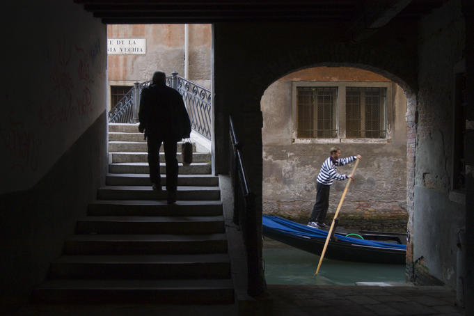 Man walking near gondola, classic Venician scene.