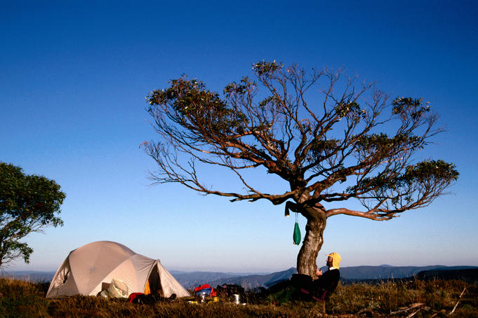 Bushwalker and tent on summit of Mt Speculation .