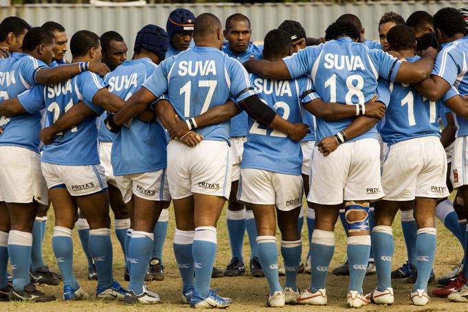 Suva rugby players linking bodies in circle at Albert park.