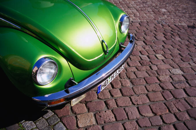 Detail of green Volkswagen parked on cobblestone street.