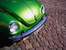 Detail of green Volkswagen parked on cobblestone street.