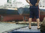 Man standing on deck of small cargo vessel in Busan Harbor.