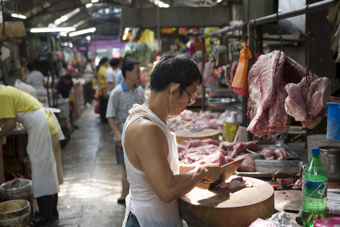 Butcher chops pork in Chinatown market.