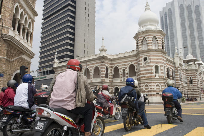Motorcyclists at stop light in front of Sultan Abdul Samad Building, High Court building.