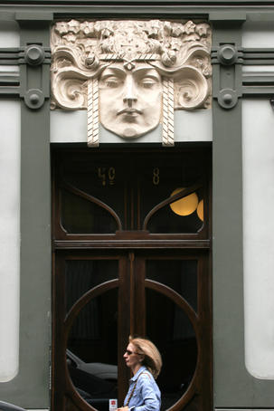 Woman walking past door of Art Nouveau building in old town Riga.