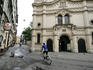 Person riding bike through old Jewish quarter, with Synagoga Tempel in background.