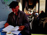 Man reading book and smoking at outdoor cafe.