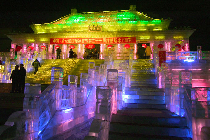 Illuminated ice sculpture of traditional architecture at Ice Festival.