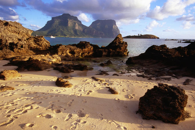 Foot steps on sand with view out to sea.