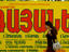 Young woman walking in front of billboard.