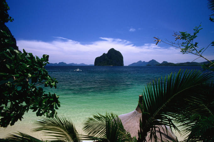 Rock outcrops in sea through tropical fronds.