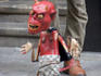 Street entertainer operating devil puppet.