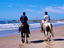 Horseback riding on beach with Polonio in background.