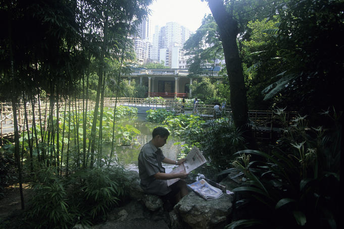 Man reading newspaper in Lou Lim Ieoc Garden.