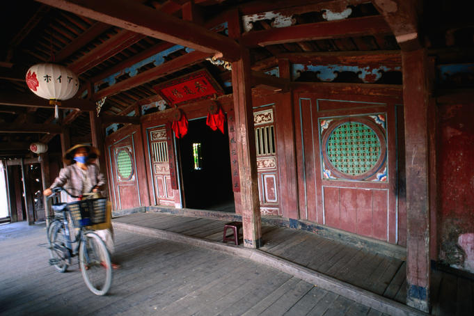 Woman with bicycle crossing a footbridge in Hoi An.