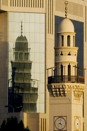 Mosque in front of glass-fronted building.