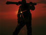 Skier standing on top of mountain above fjords and midnight sun.