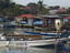 Man standing on jetty near boats in harbour.