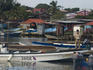 Man standing on jetty near boats in harbour.