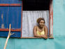 Woman at window of colourful house, Little Corn Island.