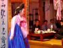 Woman in costume performing for table of men dining at Sanchon, Insadong.
