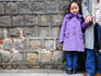 Portrait of young girl standing against stone wall.