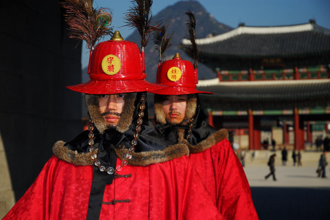 Gyeongbokgung palace guards with palace, mountains in background, Gwanghwamun.