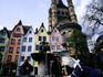 Children playing with water in a fountain in the old town (Altstadt) with heritage buildings and the Romanesque Church of Gross Saint Martin in the background.