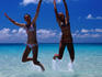 Teenage girls jumping in shallows off Whitehaven Beach in the Whitsunday Islands.
