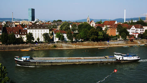 Long freight ship on Rhine River in front of houses at Kleinbasel.