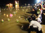 Thai families placing lighted krathong (votive candles & flowers) on Chao Phraya River during Loi Krathong lantern festival at Bangsai Royal Folk Arts and Crafts Centre.