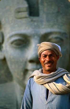 Man in front of Ramses II statue, Luxor Temple, East Bank of Nile River valley.