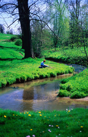 Hiker relaxing on bank of stream.