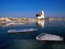 Lighthouse on frozen Ijsselmeer lake.