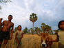 Girls assisting their father with farm work.