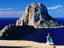 Near Sant Josep de Sa Talaia, girl on rock looking at offshore isle of Es Vedra.