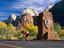 Cyclist at south entrance during autumn, with Mountain of the Sun and Twin Brothers towering above.