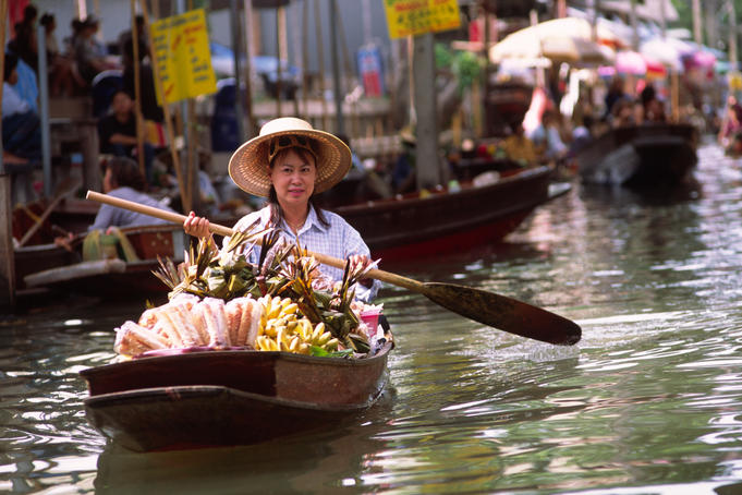 Woman paddling boat at floating market, Damnoen Sadoak.